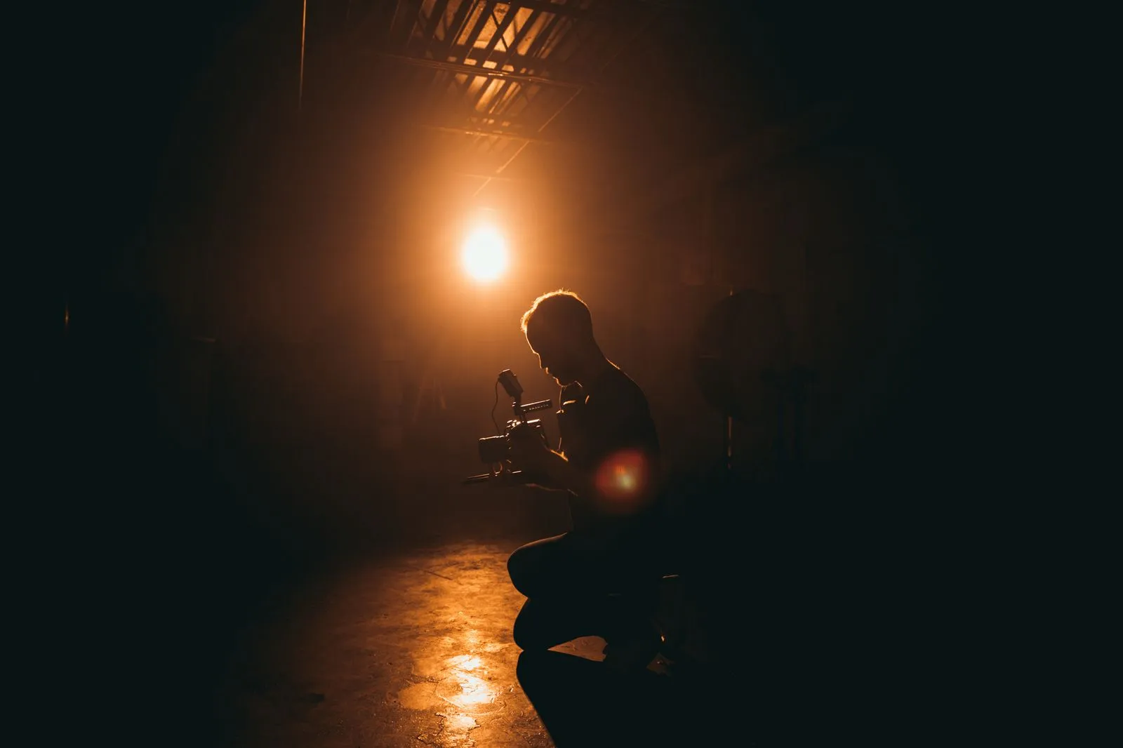 Filmmaker with camera on a lit set